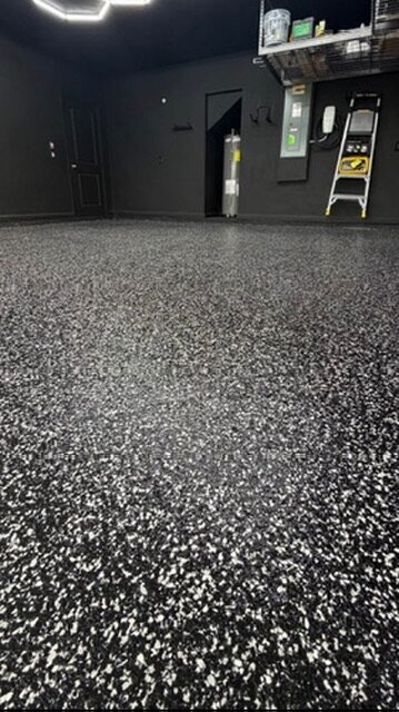 Black base epoxy floor with white flake in a dark-themed garage — Epox It Flooring